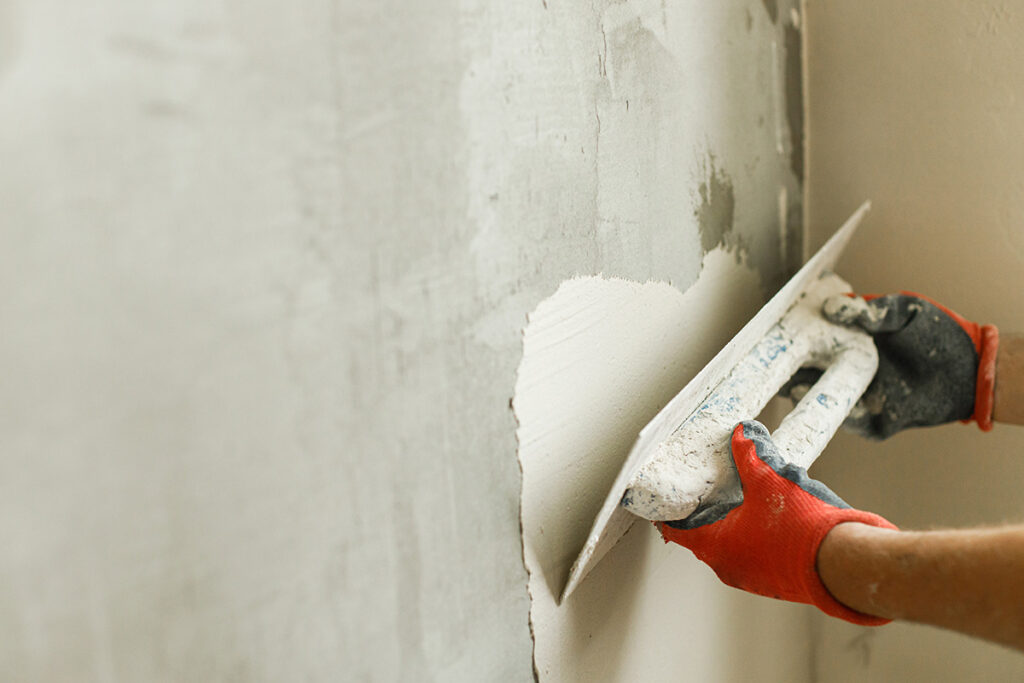 Worker plastering walls with gypsum plaster and spatula . Constr